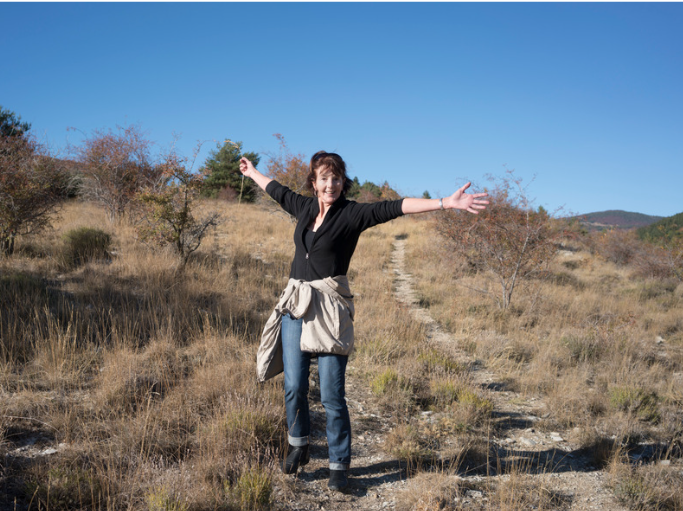 A person standing on a dirt path with her arms outstretched

Description automatically generated